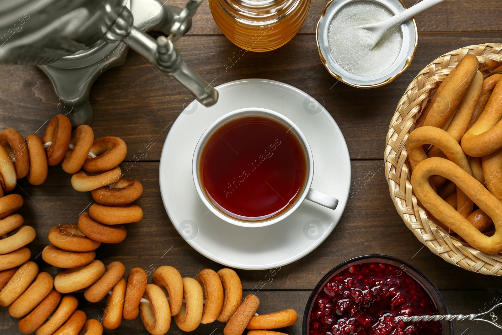 Photo of Flat lay composition with delicious ring shaped Sushki (dry bagels) and cup of tea on wooden table