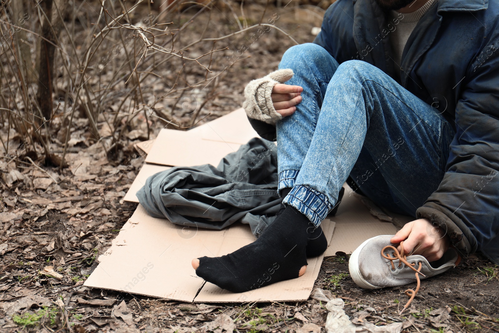 Photo of Poor homeless man sitting on ground outdoors, closeup