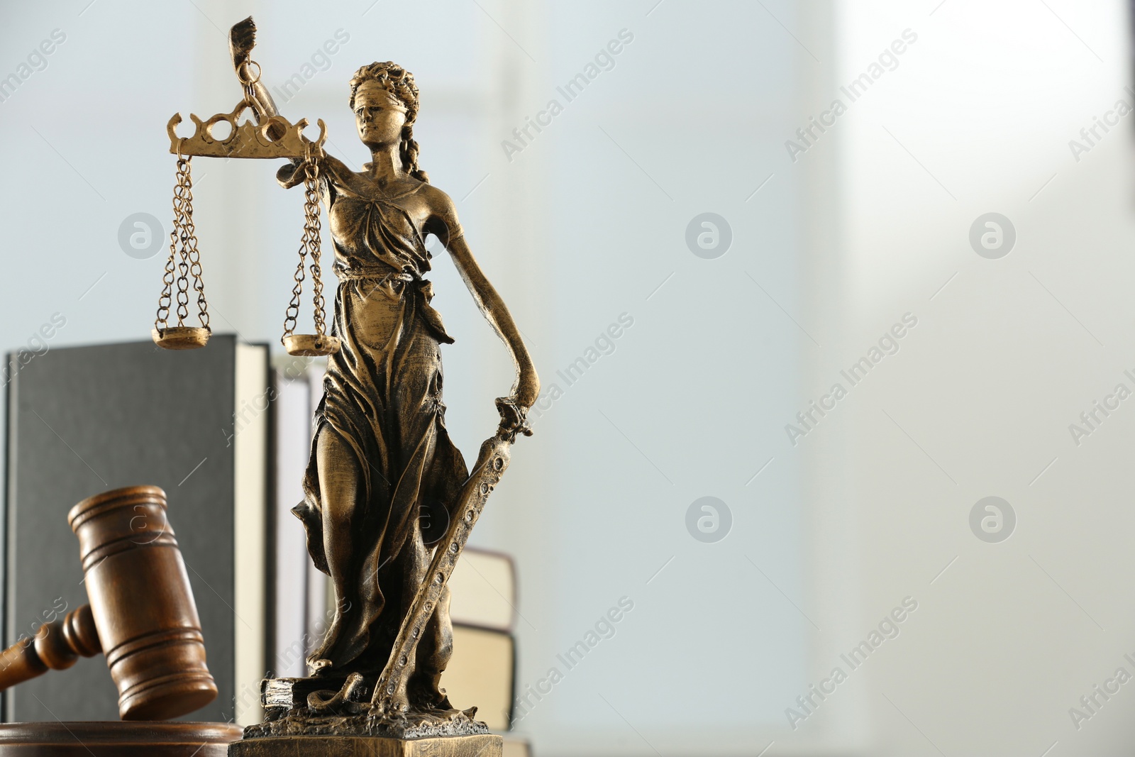 Photo of Figure of Lady Justice, gavel and books on white background, space for text. Symbol of fair treatment under law