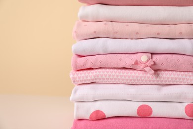 Photo of Stack of baby girl's clothes on yellow background, closeup. Space for text