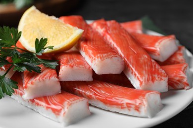 Plate of fresh crab sticks with lemon on table, closeup