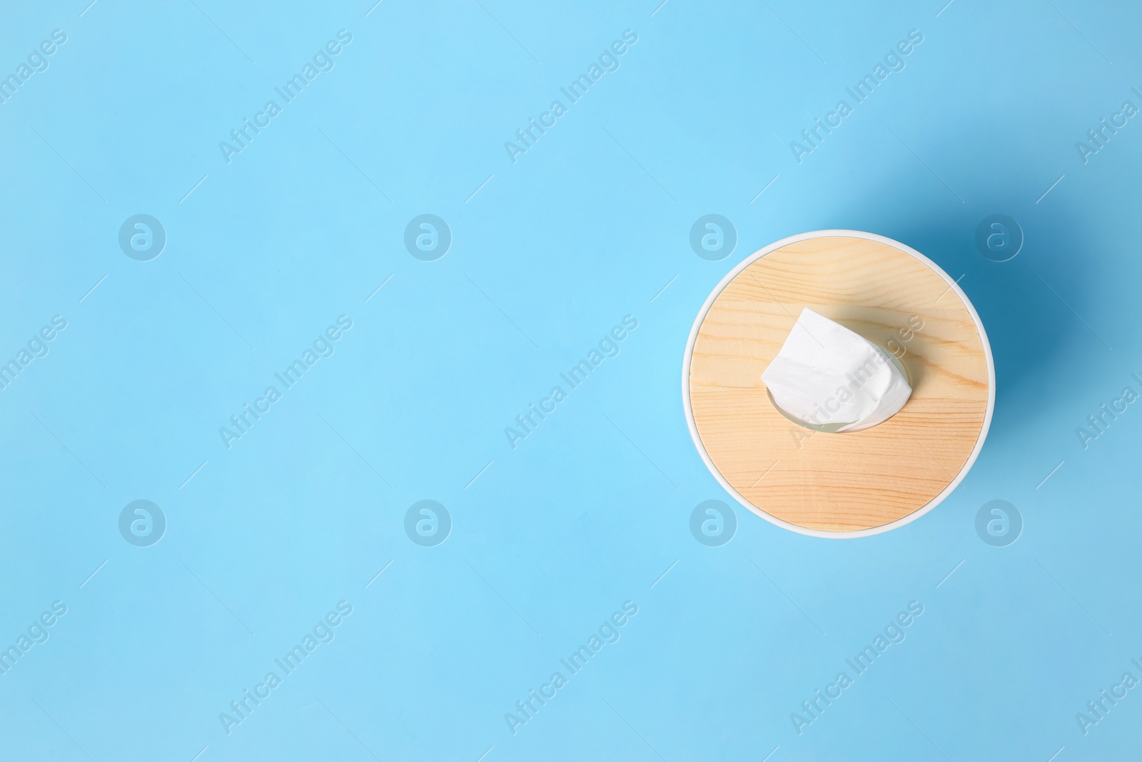 Photo of Holder with paper tissues on light blue background, top view. Space for text