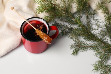 Photo of Stick with sugar crystals and cup of drink on white table