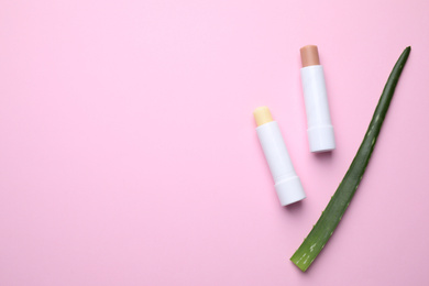 Hygienic lipsticks and aloe vera on pink background, flat lay. Space for text