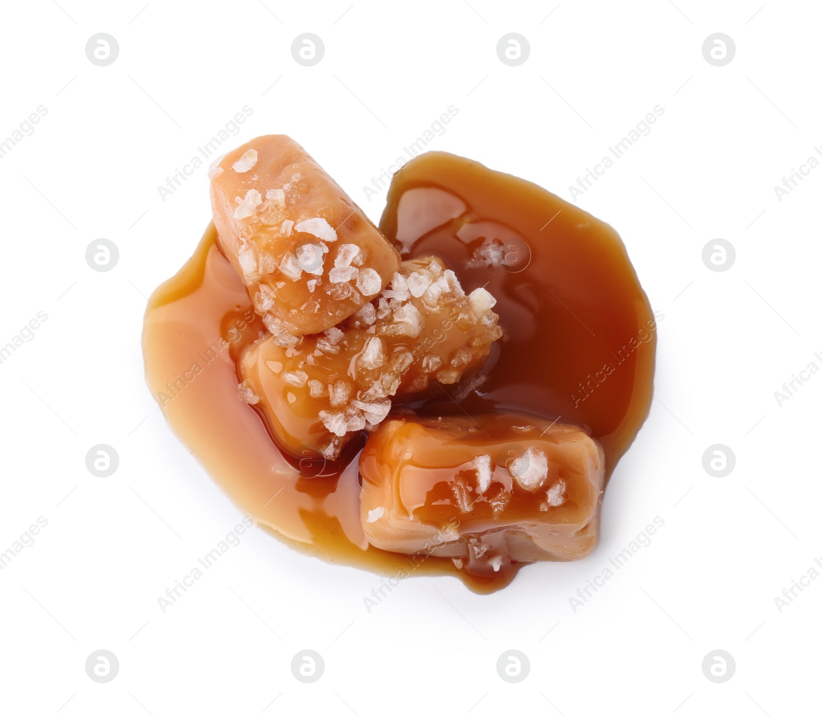 Photo of Yummy caramel candies and sea salt isolated on white, top view