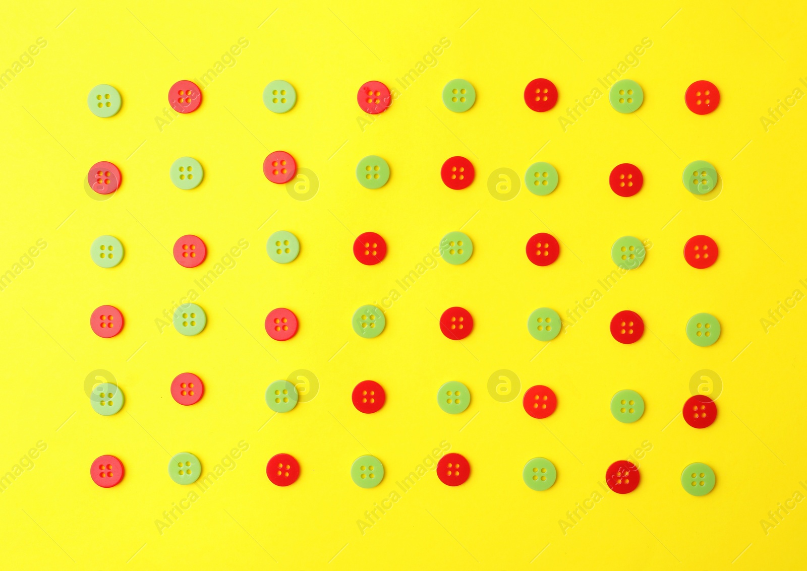 Photo of Many red and green sewing buttons on yellow background, flat lay