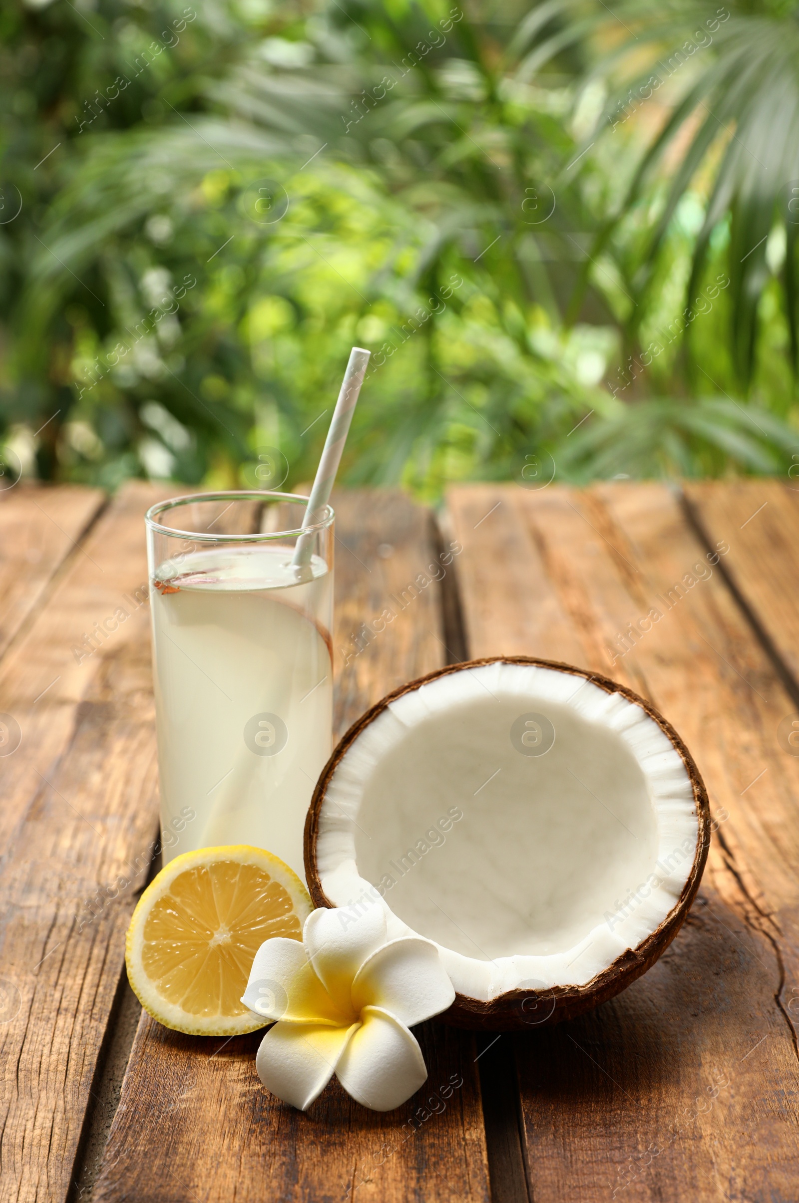 Photo of Composition with glass of coconut water and lemon on wooden table