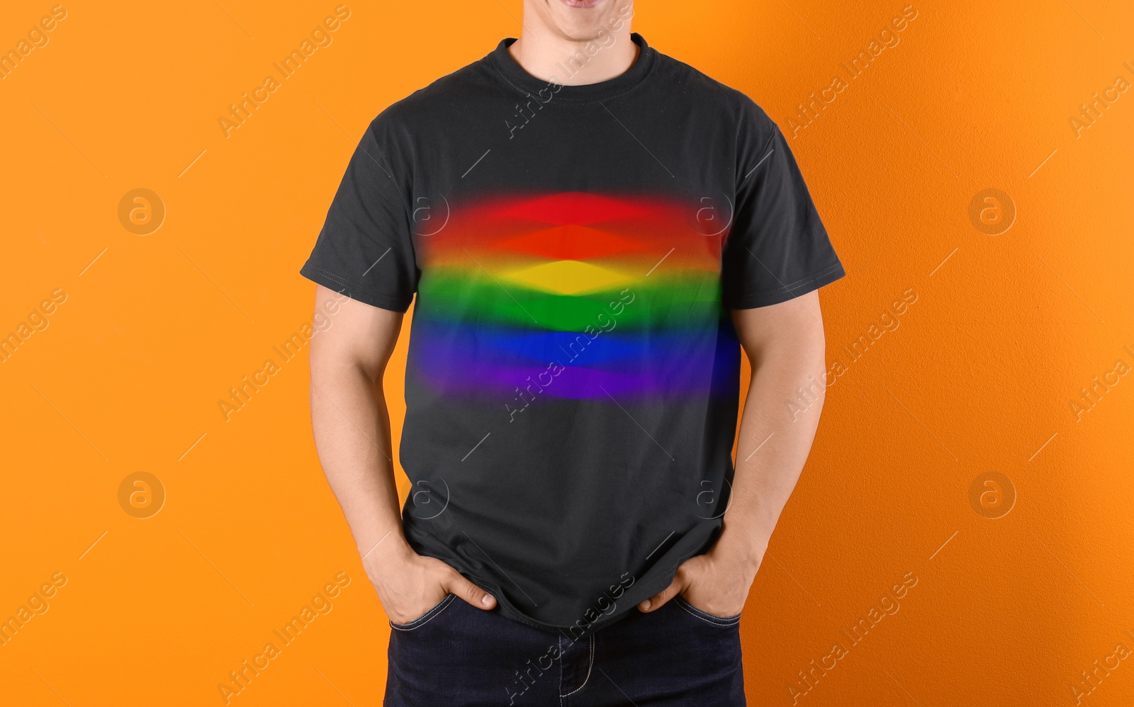 Image of Young man wearing black t-shirt with image of LGBT pride flag on orange background