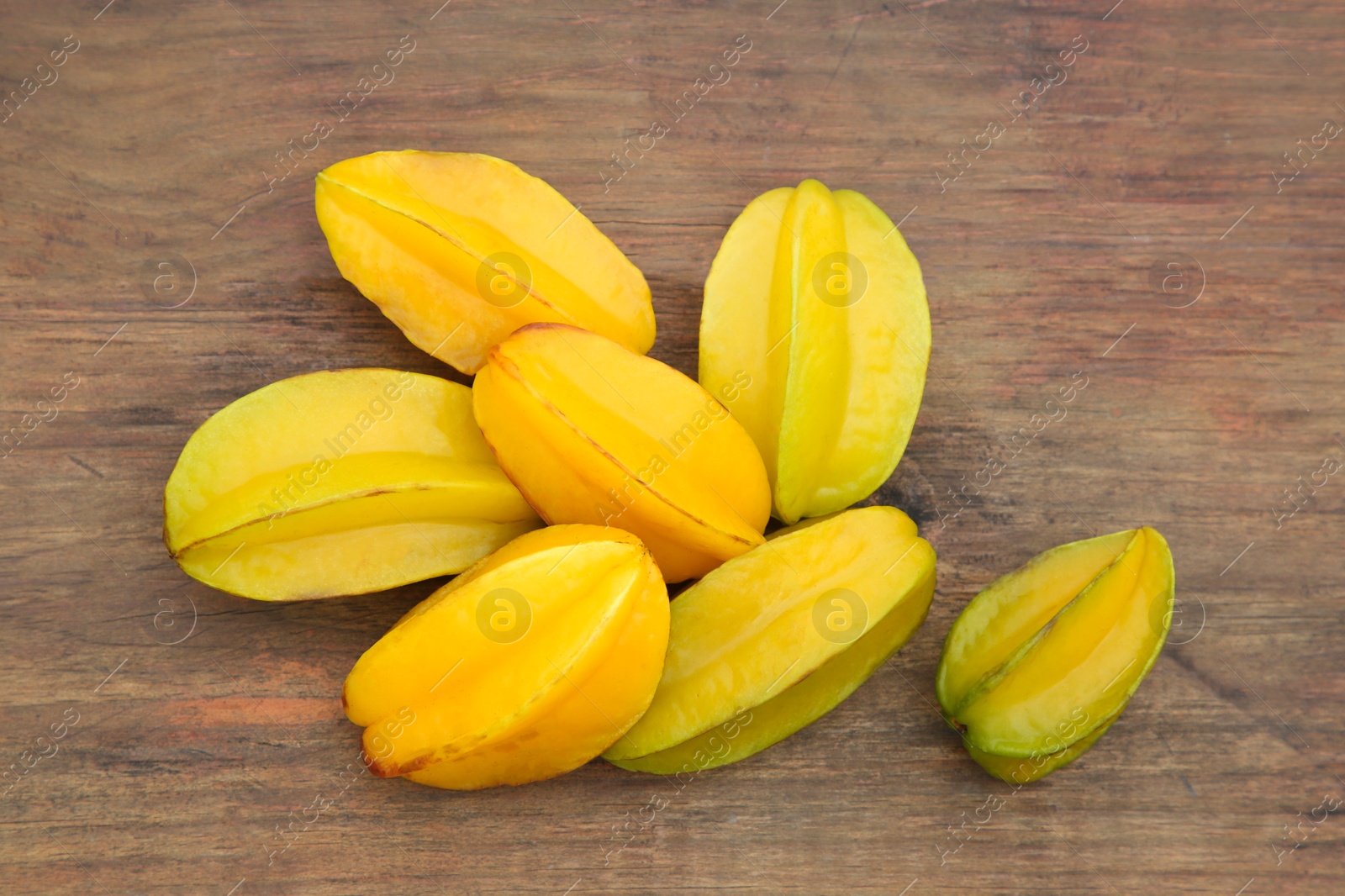 Photo of Many delicious ripe carambolas on wooden table