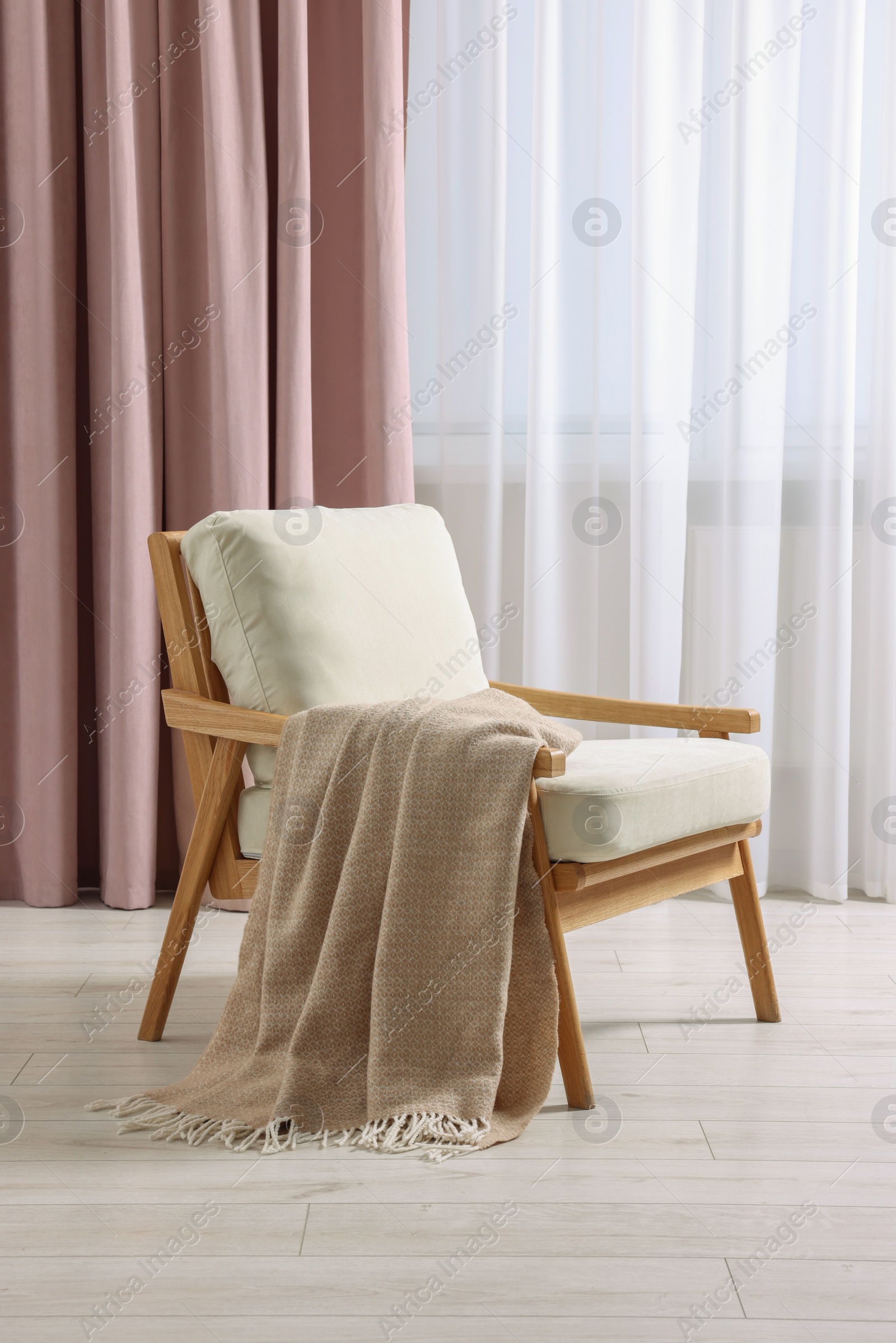 Photo of Stylish comfortable armchair with blanket in room