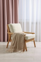 Stylish comfortable armchair with blanket in room