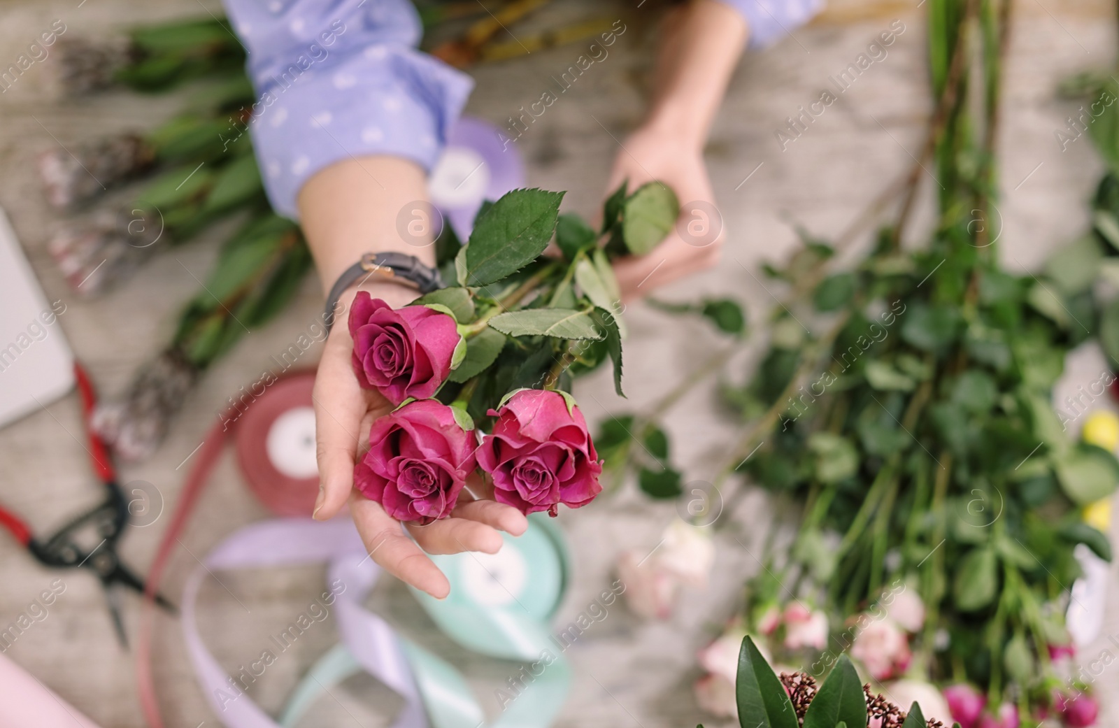 Photo of Female florist making beautiful bouquet in flower shop, closeup