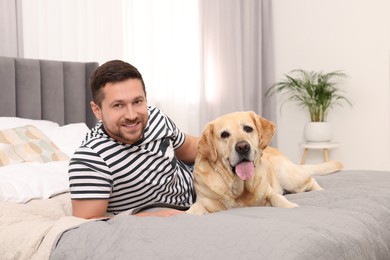 Photo of Man with adorable Labrador Retriever dog on bed at home. Lovely pet