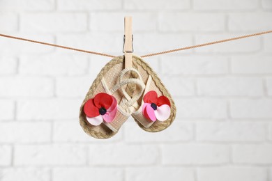 Photo of Cute baby shoes drying on washing line against white brick wall