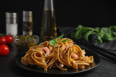 Photo of Tasty buckwheat noodles with shrimps served on black table