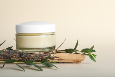 Photo of Composition with jar of body cream and eucalyptus on beige background