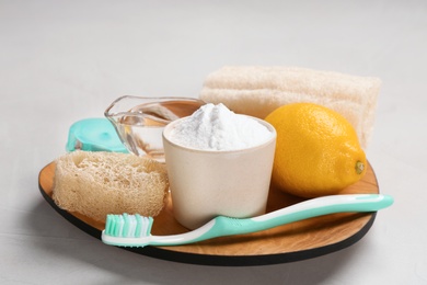 Photo of Bowl with baking soda, lemon and cleaning items on plate