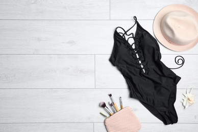 Photo of Flat lay composition with one-piece swimsuit and accessories on wooden background