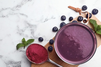 Flat lay composition with tasty acai drink, powder and berries on marble table