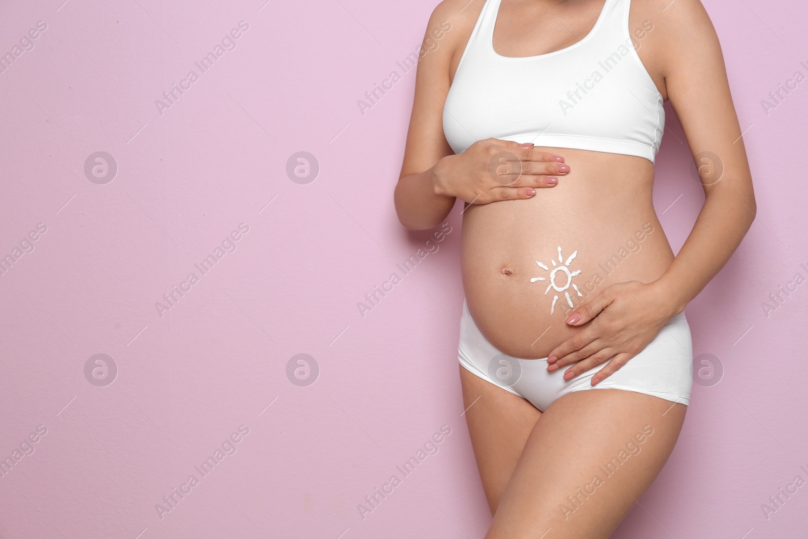 Photo of Sun painted with body cream on pregnant woman's belly against color background, closeup. Space for text