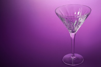 Photo of Elegant empty martini glass on purple background. Space for text