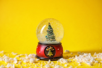 Photo of Snow globe with Christmas tree on color background