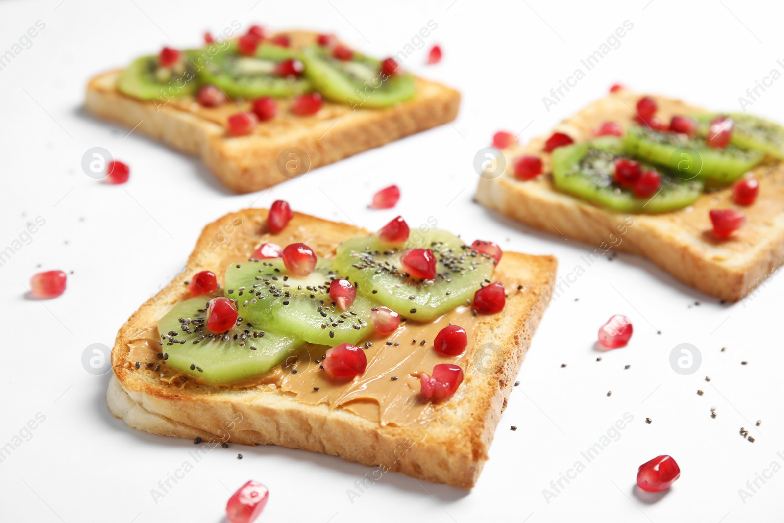 Photo of Tasty toasts with kiwi, peanut butter, pomegranate and chia seeds on white background