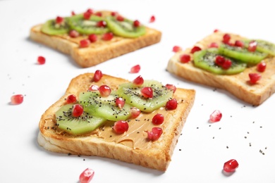 Photo of Tasty toasts with kiwi, peanut butter, pomegranate and chia seeds on white background