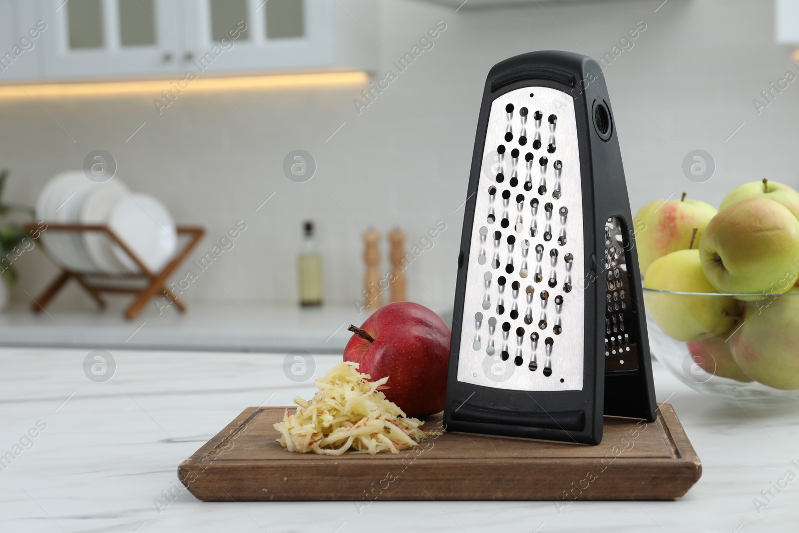 Photo of Grater and fresh ripe apples on white table in kitchen. Space for text