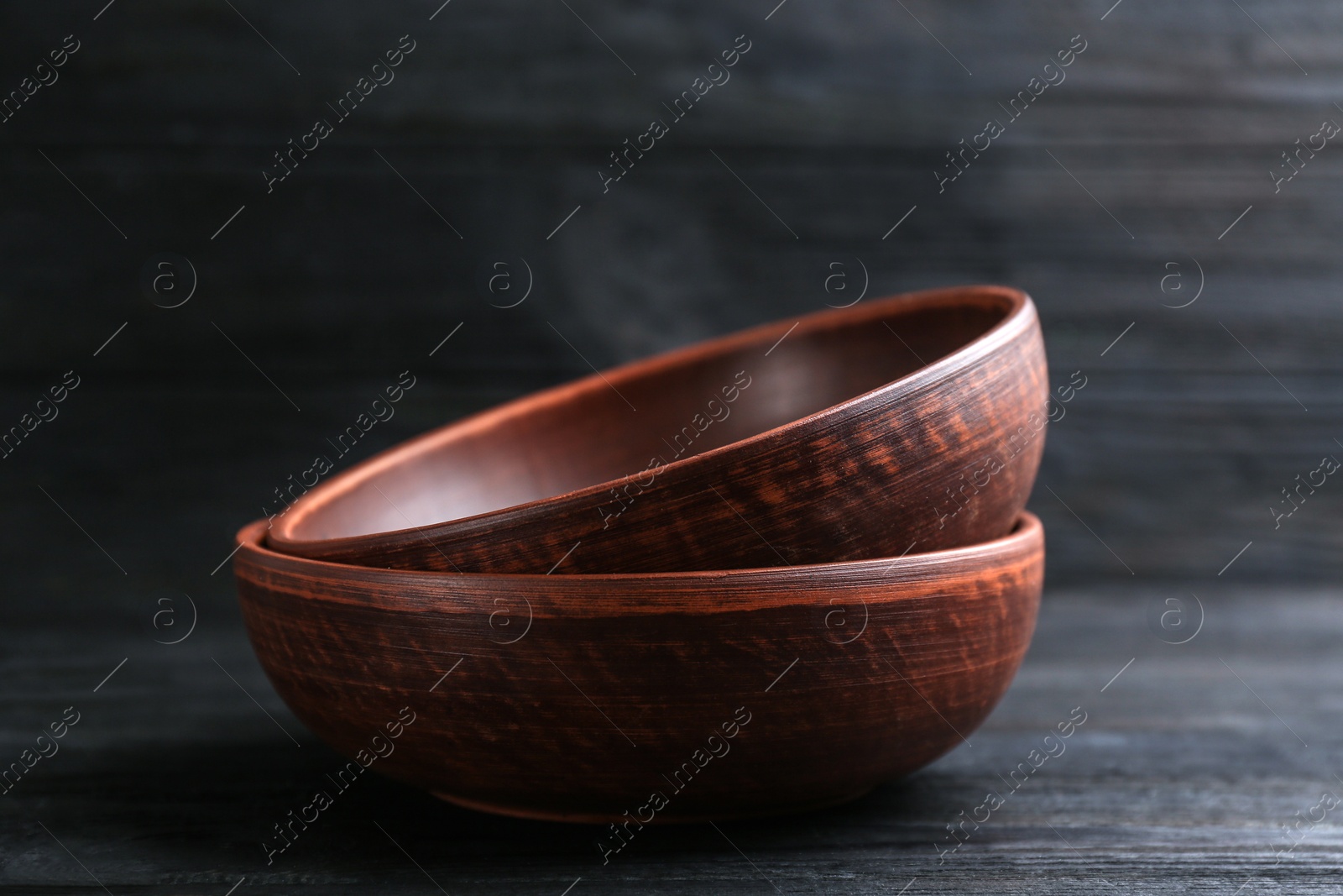 Photo of Clay bowls on black wooden table. Handmade utensils