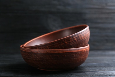 Photo of Clay bowls on black wooden table. Handmade utensils