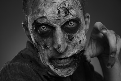 Photo of Closeup view of scary zombie on dark background, black and white effect. Halloween monster
