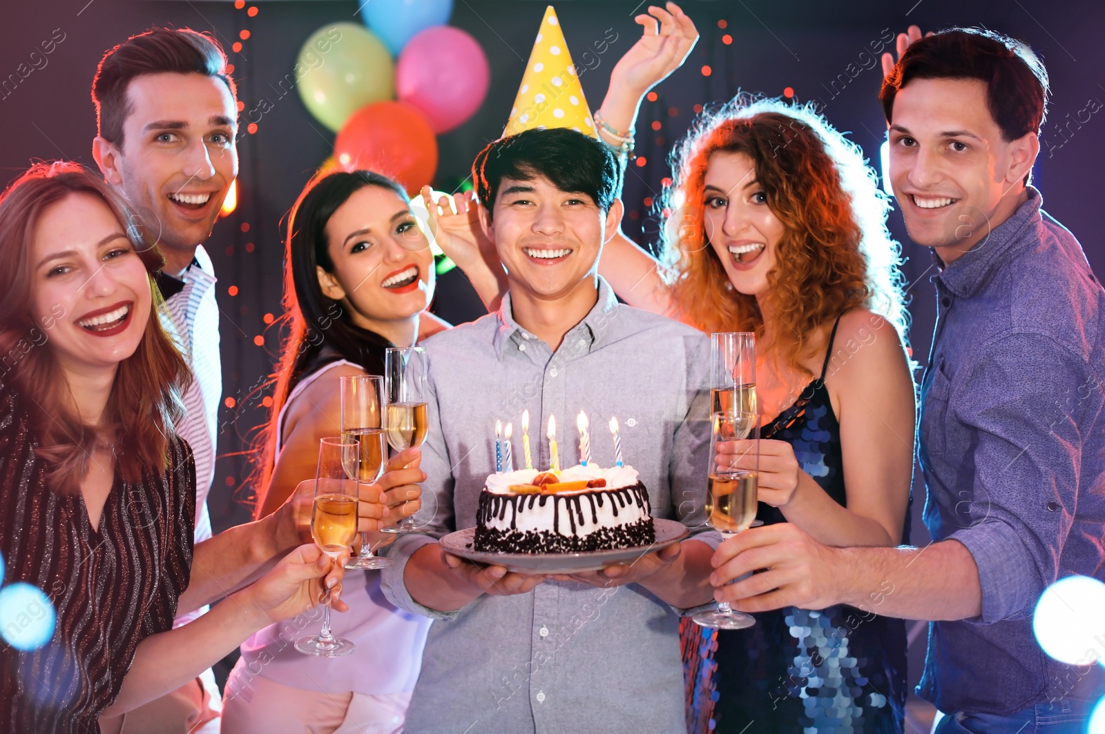 Photo of Young people celebrating birthday with cake in nightclub