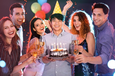 Photo of Young people celebrating birthday with cake in nightclub