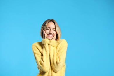 Photo of Beautiful young woman wearing knitted sweater on light blue background