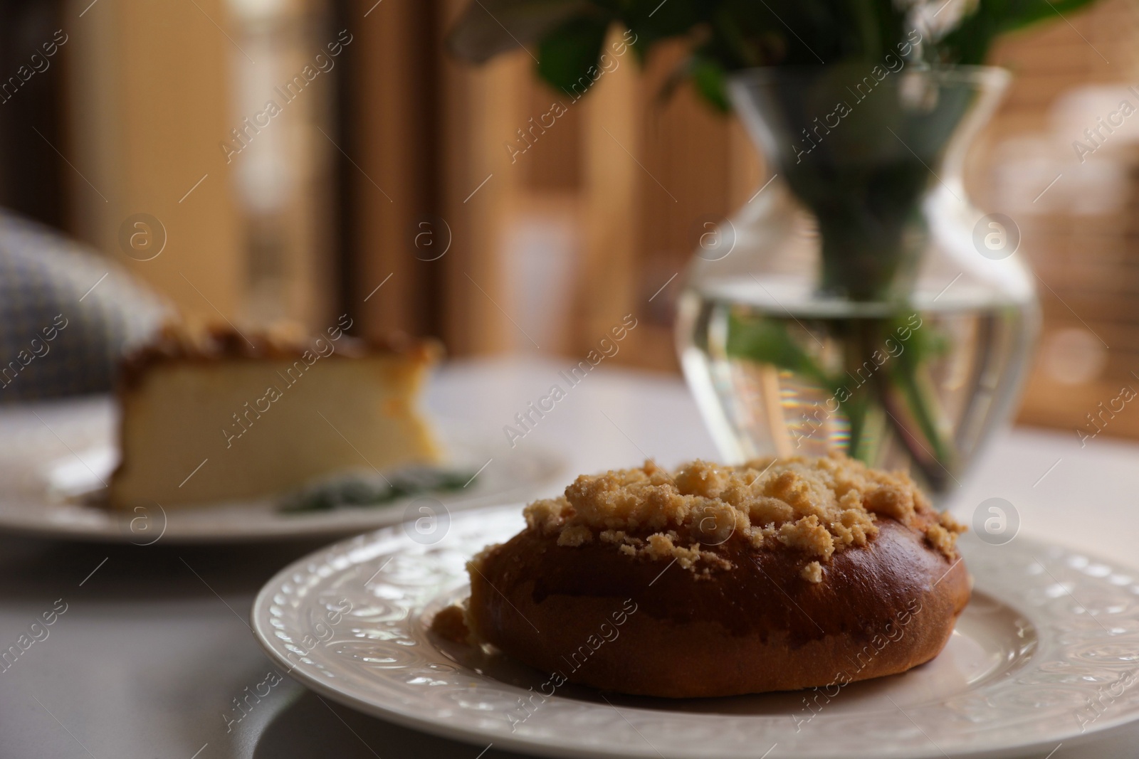 Photo of Tasty bun and cheesecake on table indoors