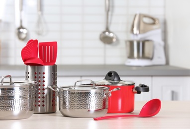 Photo of Set of clean cookware and utensils on table in kitchen