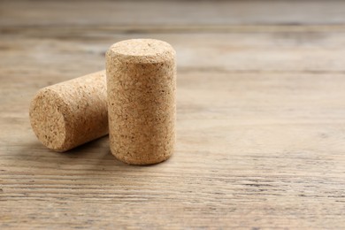 Photo of Corks of wine bottles on wooden table, closeup. Space for text