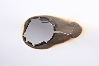 Photo of Burnt hole in paper on white background