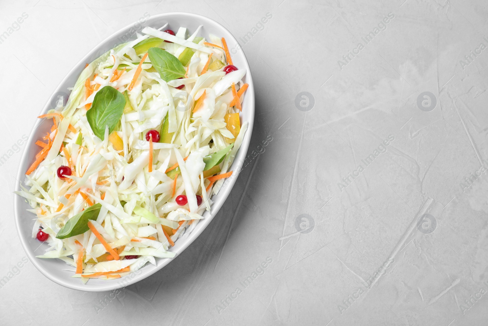 Photo of Fresh cabbage salad on light grey table, top view. Space for text