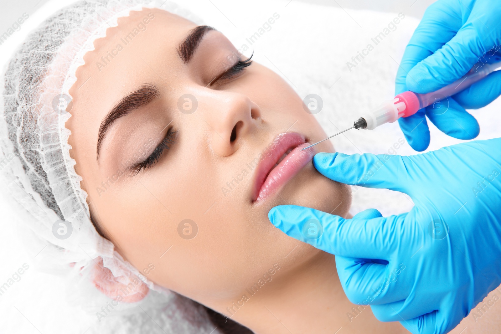 Photo of Young woman getting lip injection in beautician salon