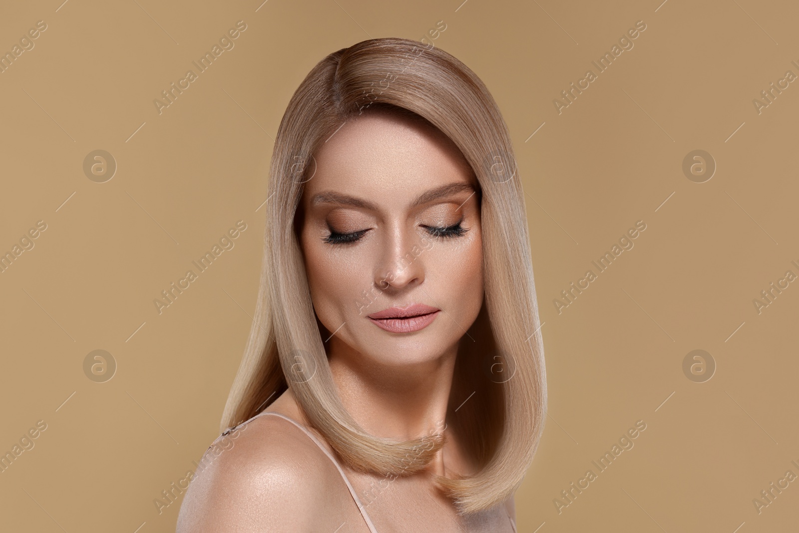 Image of Portrait of attractive woman with blonde hair on dark beige background