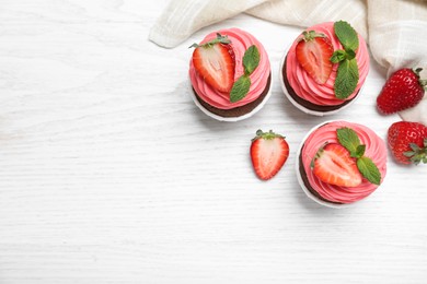 Photo of Sweet cupcakes with fresh strawberries on white wooden table, flat lay. Space for text
