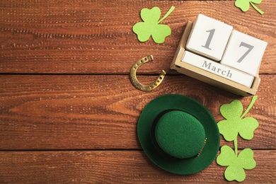 Leprechaun's hat, block calendar and St. Patrick's day decor on wooden background, flat lay. Space for text