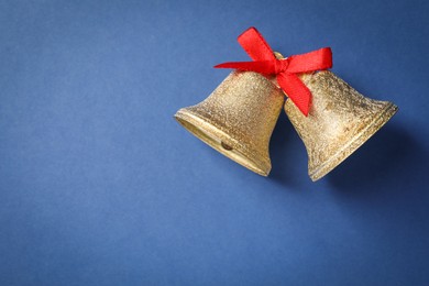 Photo of Bells with red bow on blue background, top view and space for text. Christmas decor