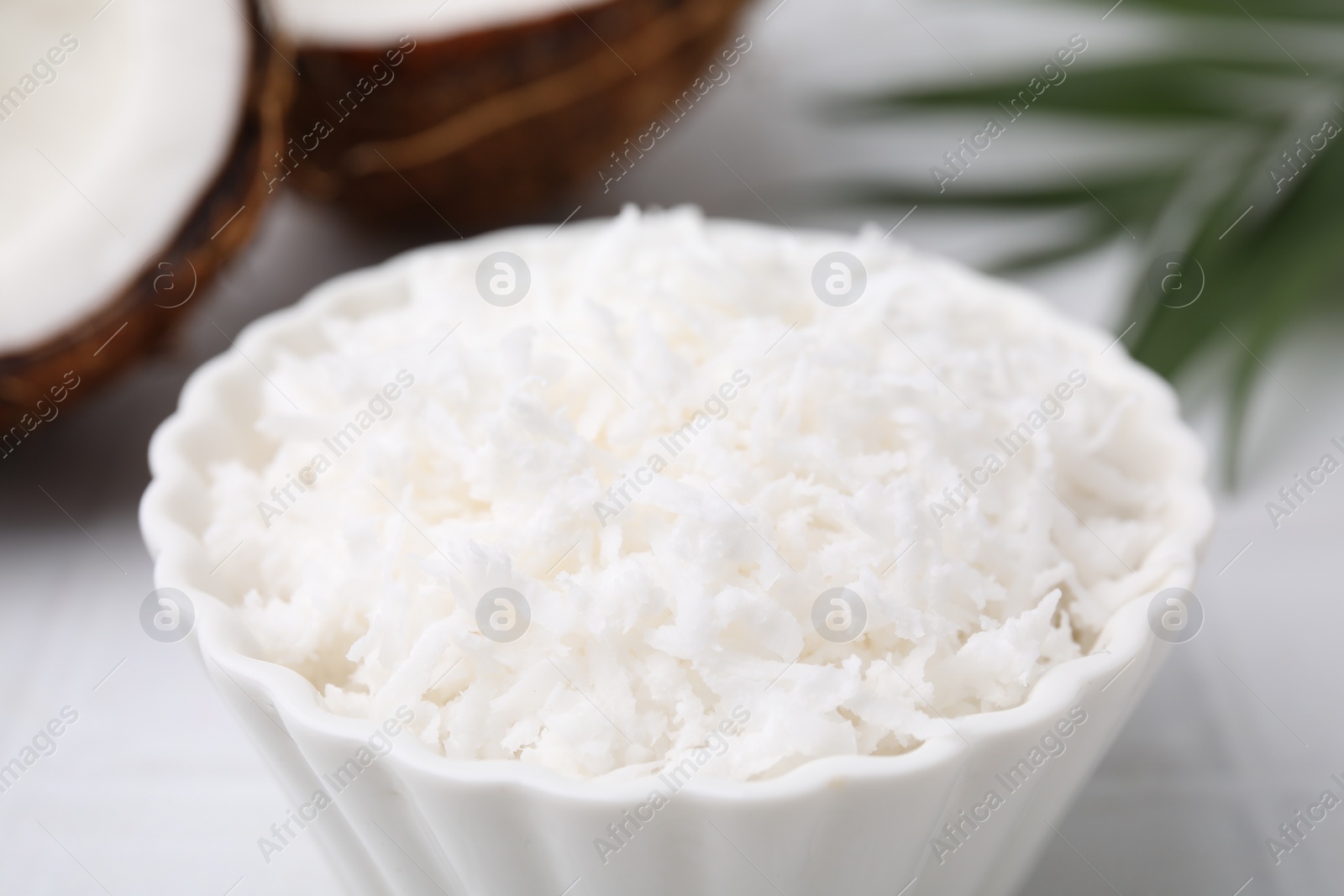 Photo of Coconut flakes in bowl on table, closeup