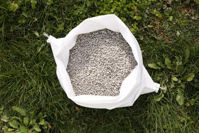 Photo of Fertilizer in bag on green grass outdoors, top view