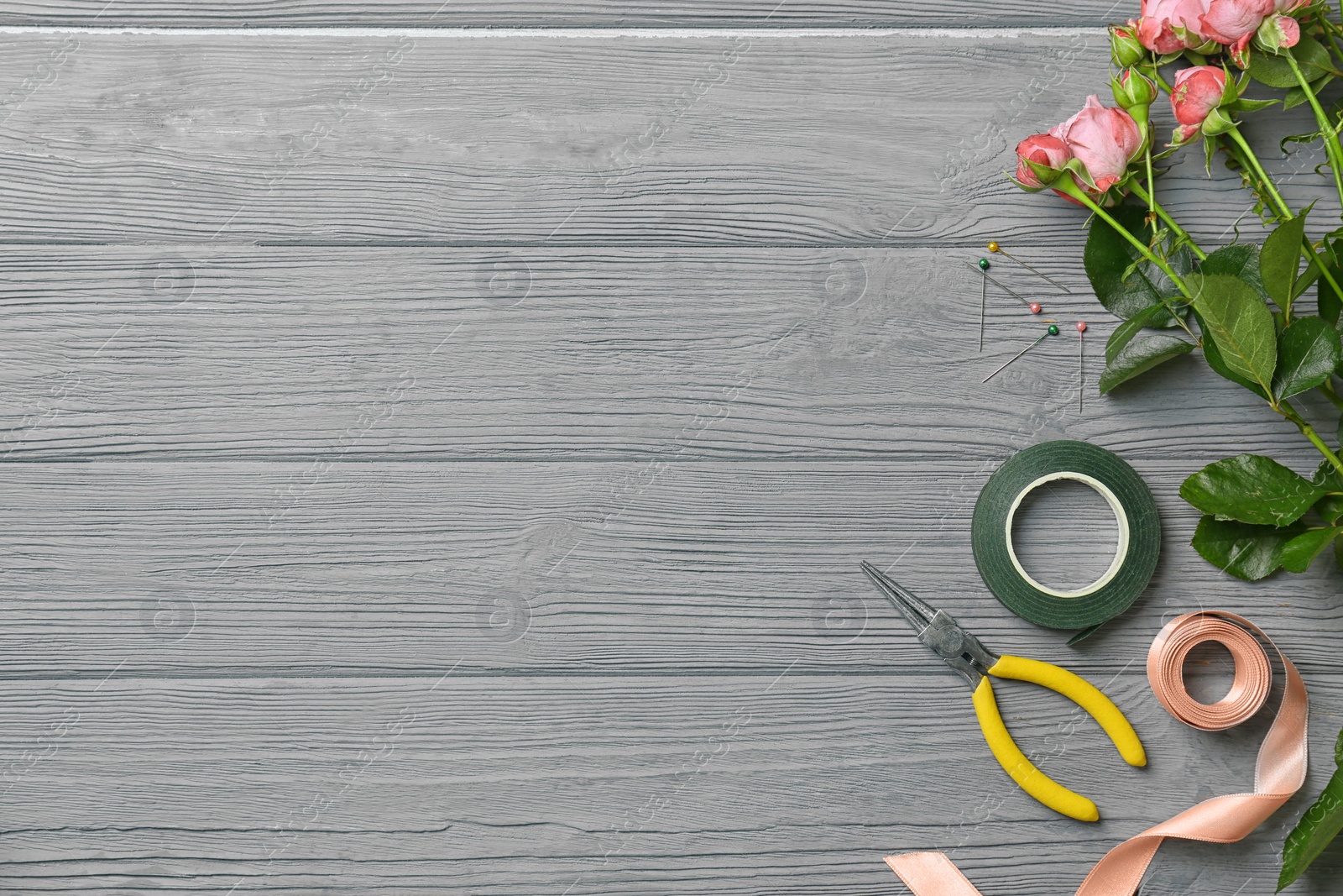 Photo of Florist equipment with flowers on wooden background, top view