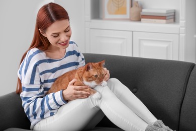 Photo of Happy woman with her cute cat on sofa at home