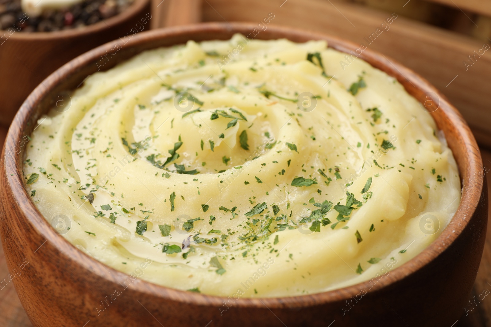 Photo of Bowl of tasty mashed potato with greens on wooden table, closeup